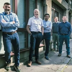 A group shot showing 5 members of the IT Foundations team casually standing outside the front of their office.