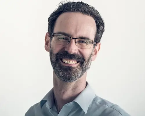 A headshot photograph of a relaxed, smiling Alastair Struthers